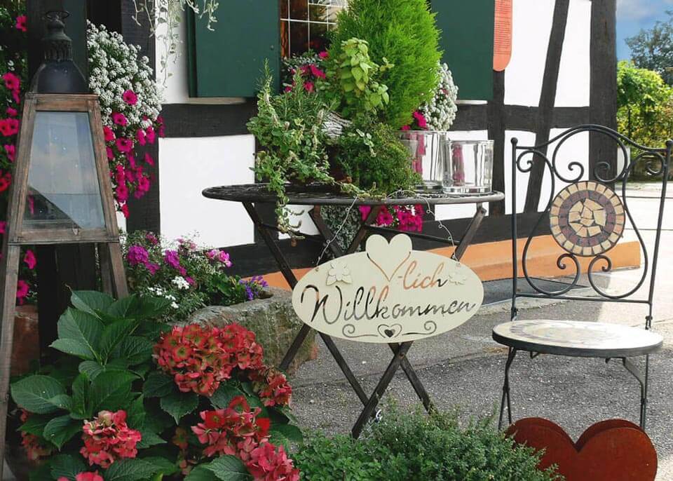 Entrance area with green plants, table and chairs and welcome sign