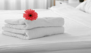 weiße Handtücher auf einem Hotelbett mit einer Blume
