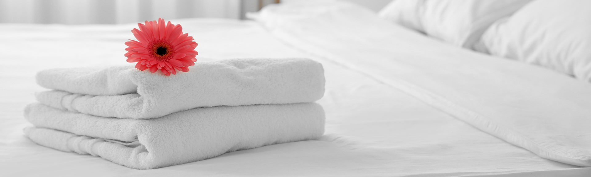 white towels on a hotel bed with a flower