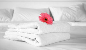 weiße Handtücher auf einem Hotelbett mit einer Blume