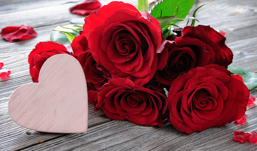 Red roses on wooden background with a heart