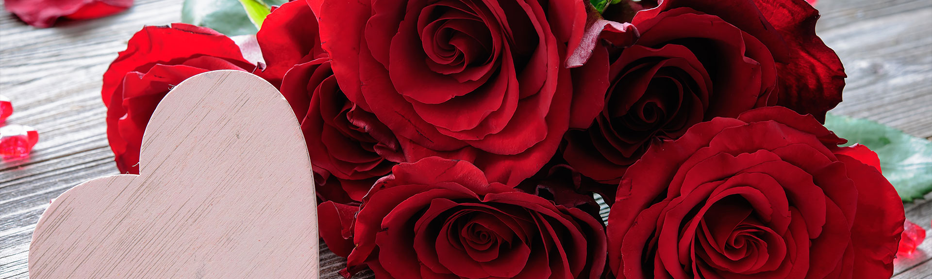 Red roses on wooden background with a heart