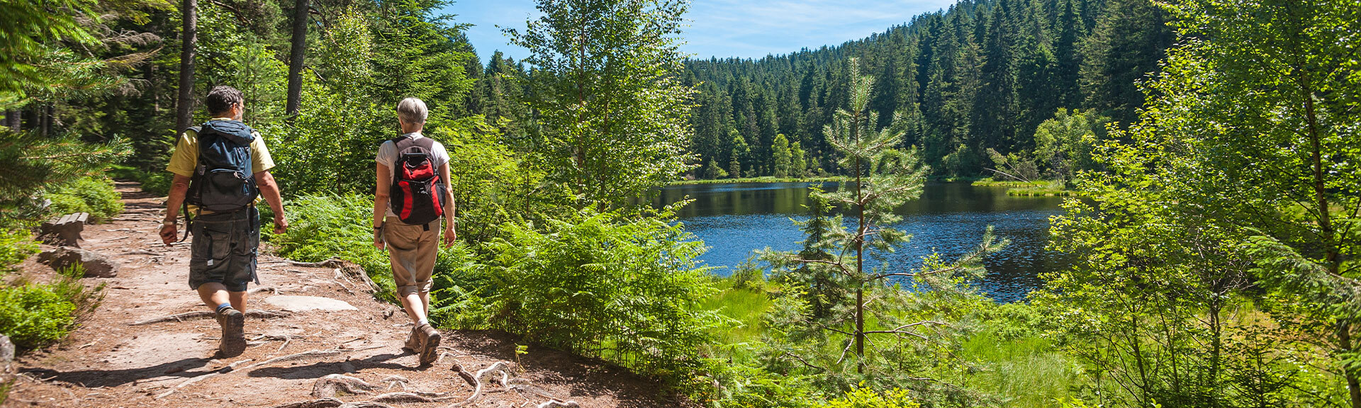 2 Personen wandern im Schwarzwald an einem See entlang