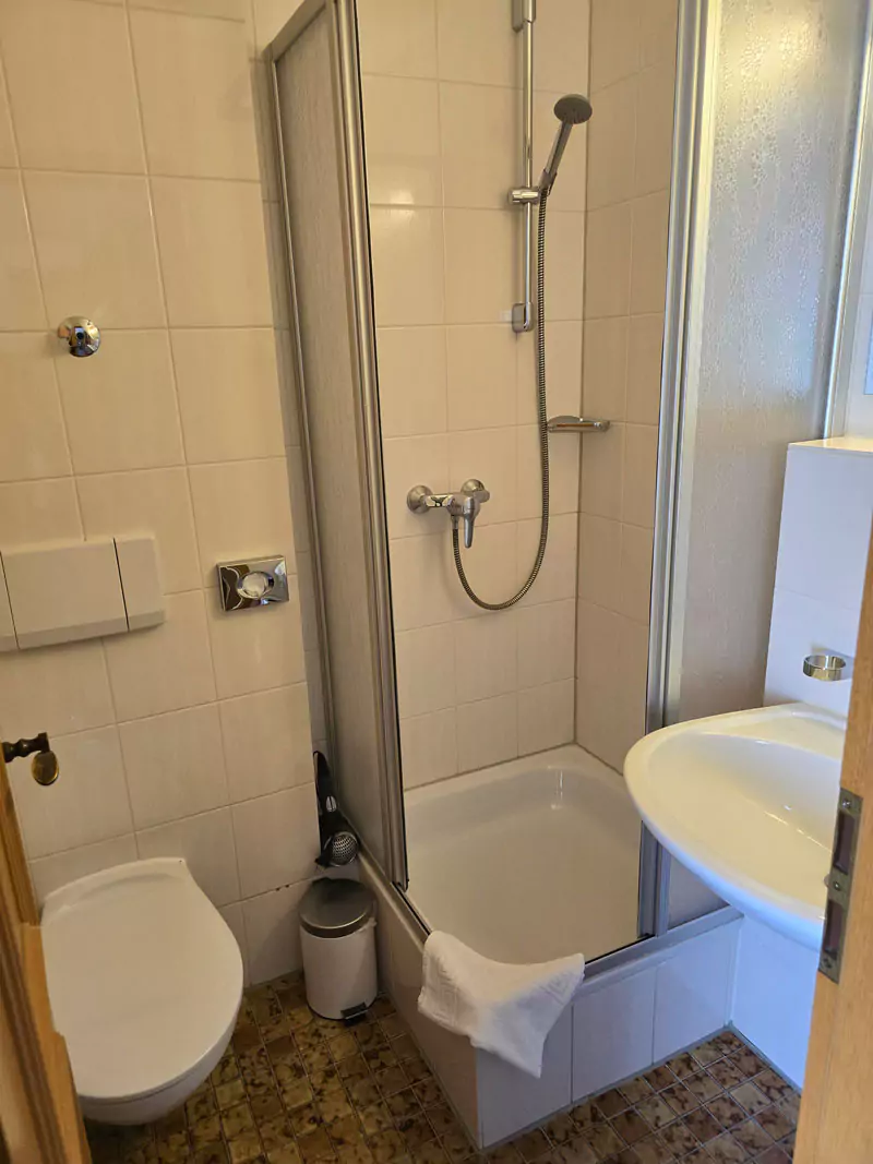 Blick in ein Badezimmer mit Dusche, WC und Waschbecken